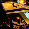 Individual waving Israeli flag at night in Jerusalem.